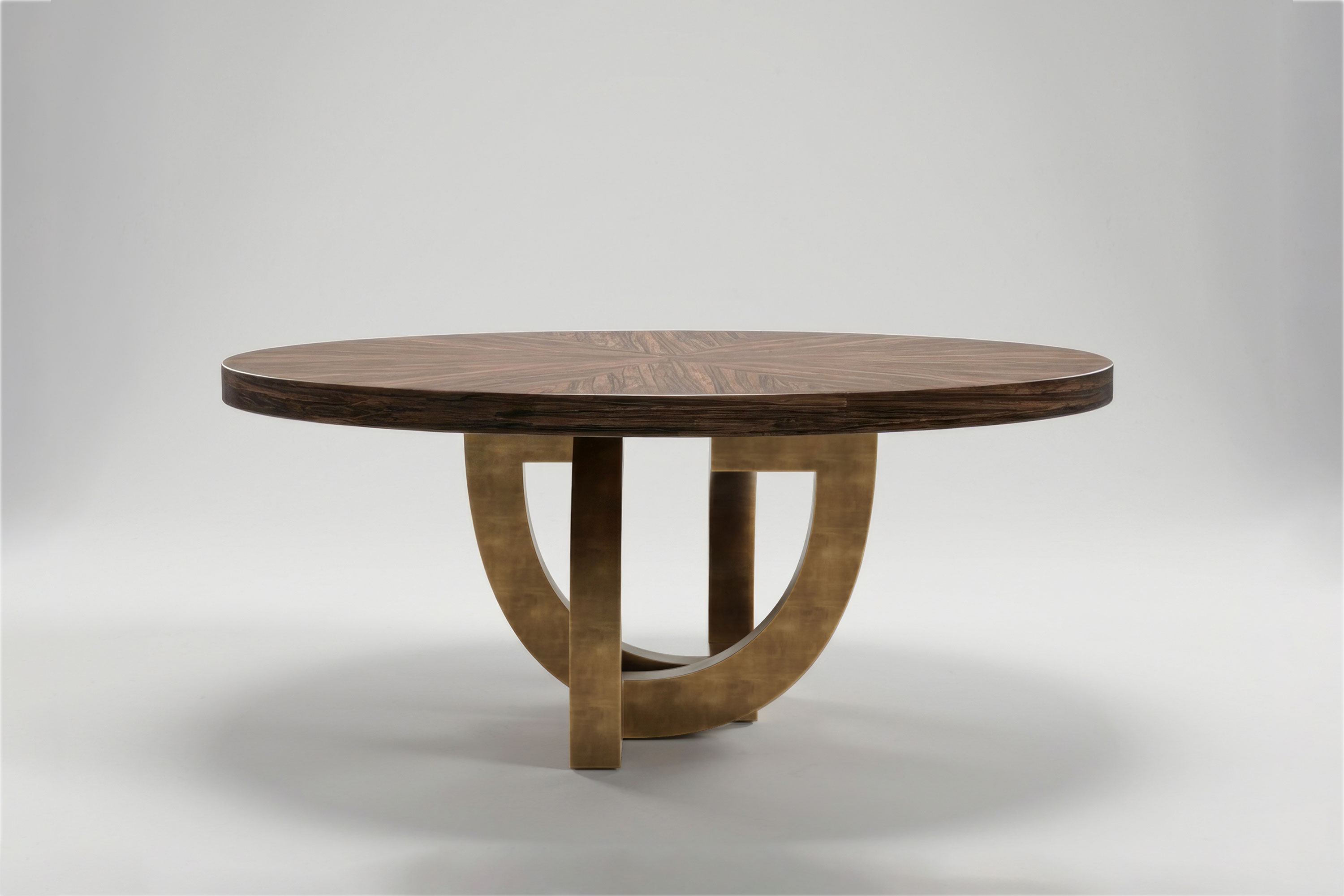 Arco Round dining table by Palena Studio, side view showing the curved arches of the patina bronze base beneath the round Macassar Ebony top
