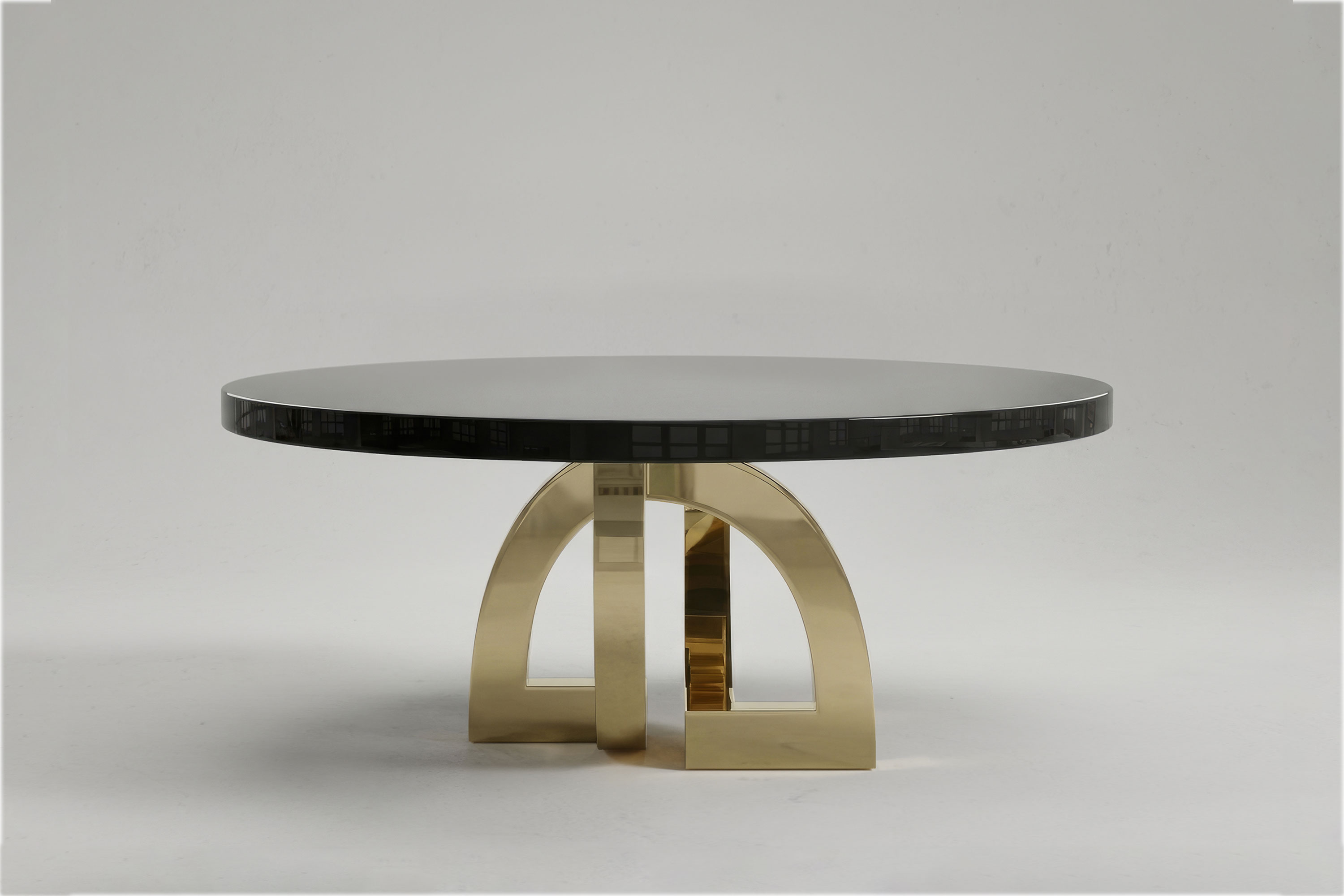 Arco Round dining table by Palena Studio, front view of the obsidian lacquer top on a polished bronze base of interlocking arches