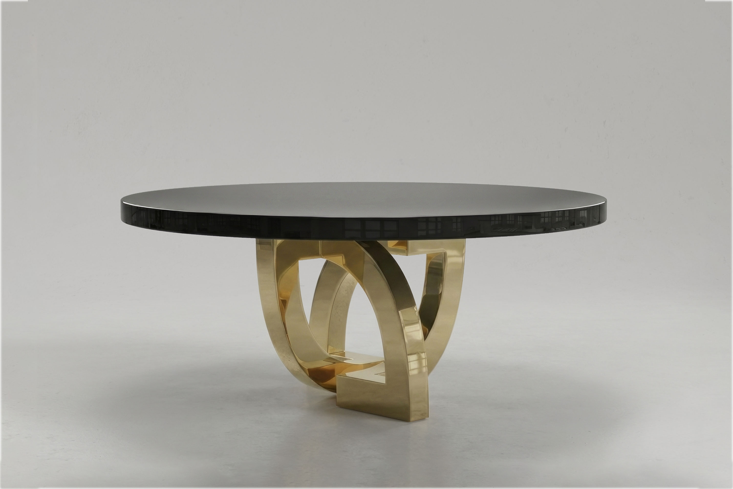 Arco Round dining table by Palena Studio, low angle view of the polished bronze arch base and the obsidian lacquer top