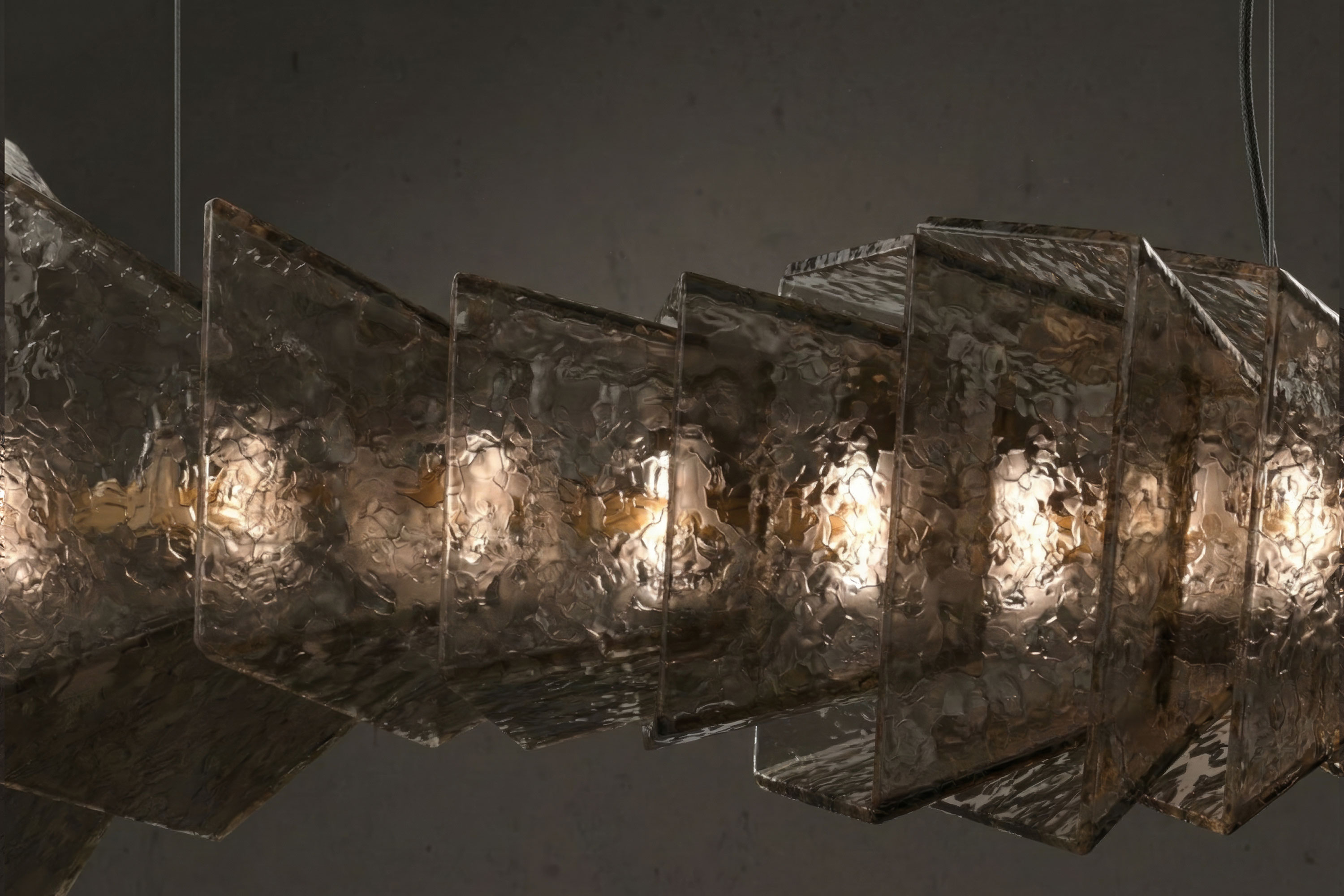 A series of textured, translucent Murano glass panels are arranged in a zigzag pattern around light bulbs, forming a modern pendant light fixture against a dark background.
