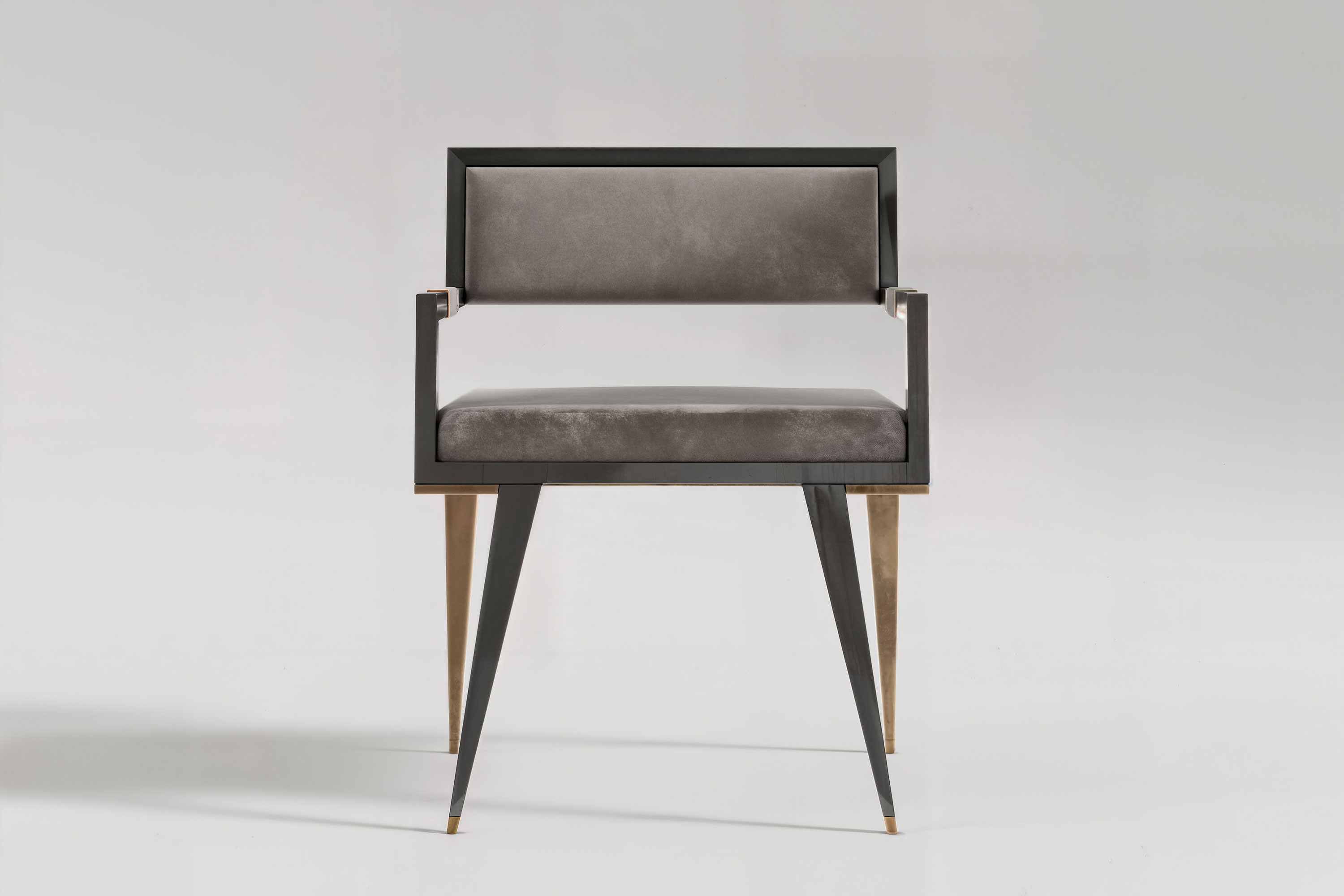 Le Loup chair from the front, the upholstered back framed in obsidian lacquer above tapered patina bronze legs.