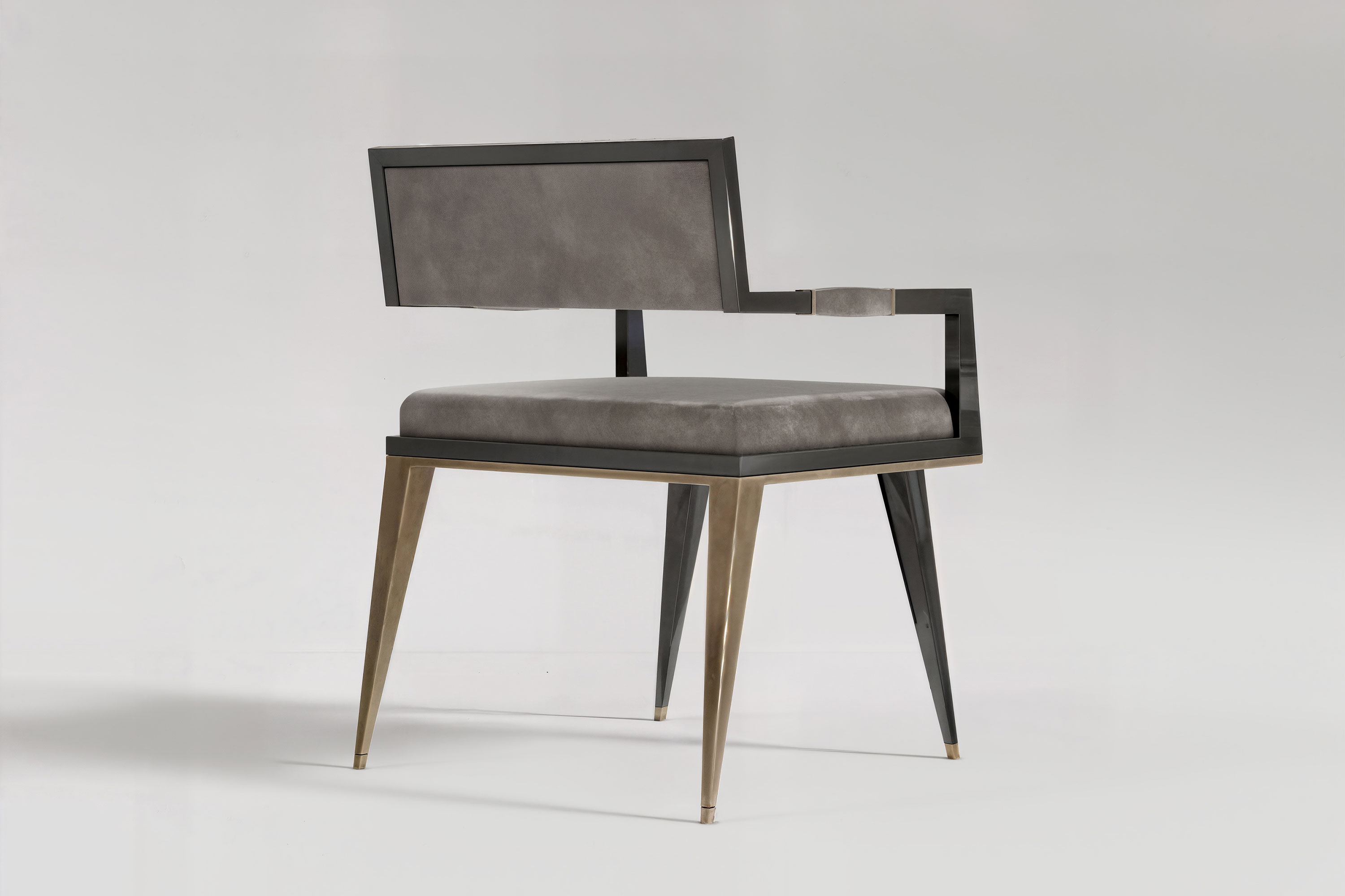 Le Loup chair seen from the side, showing the squared arm and the splay of its patina bronze legs.