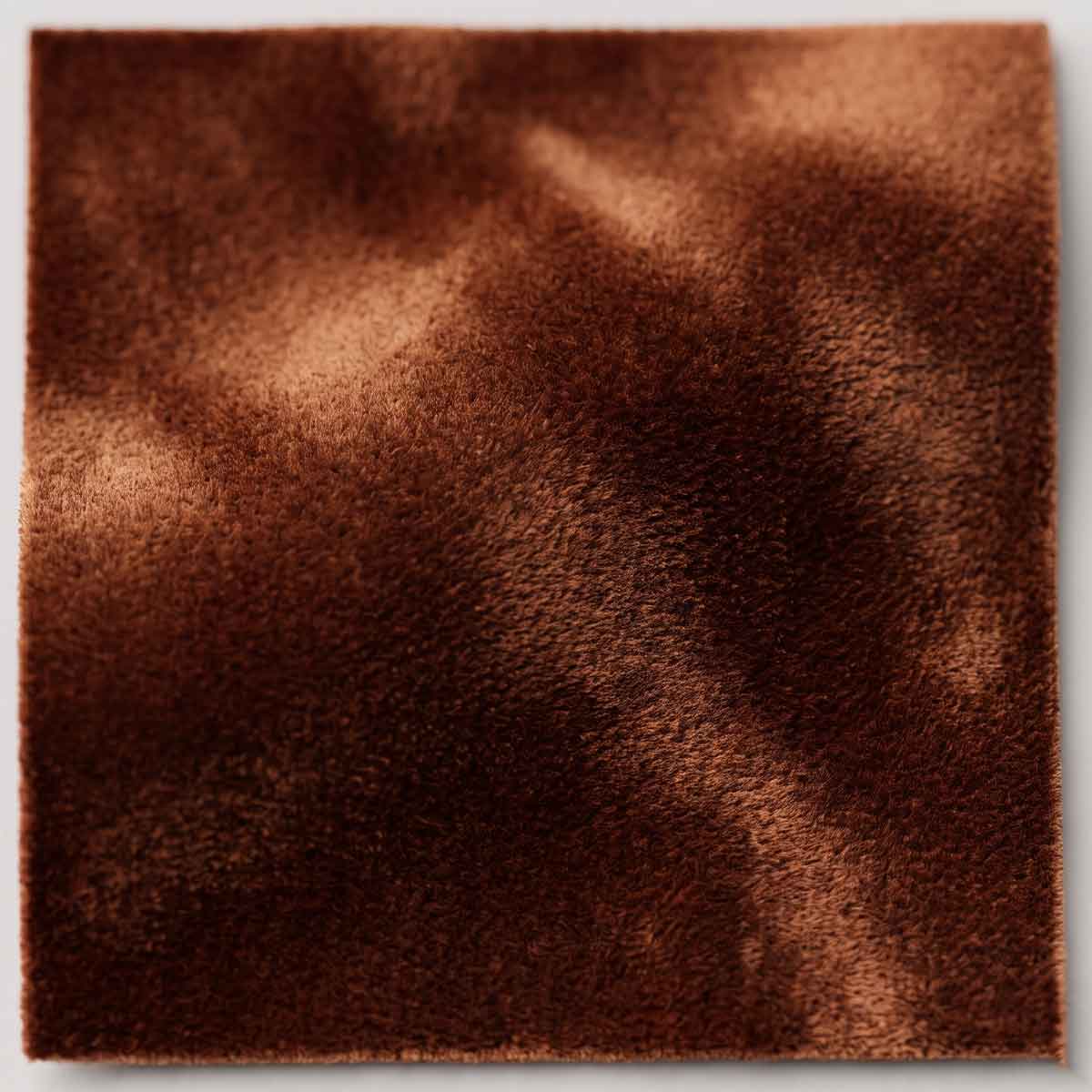 A deeply luxurious, plush silk velvet in a warm, inviting cognac hue. Its fluid drape and highly reflective pile create a captivating interplay of light and shadow.