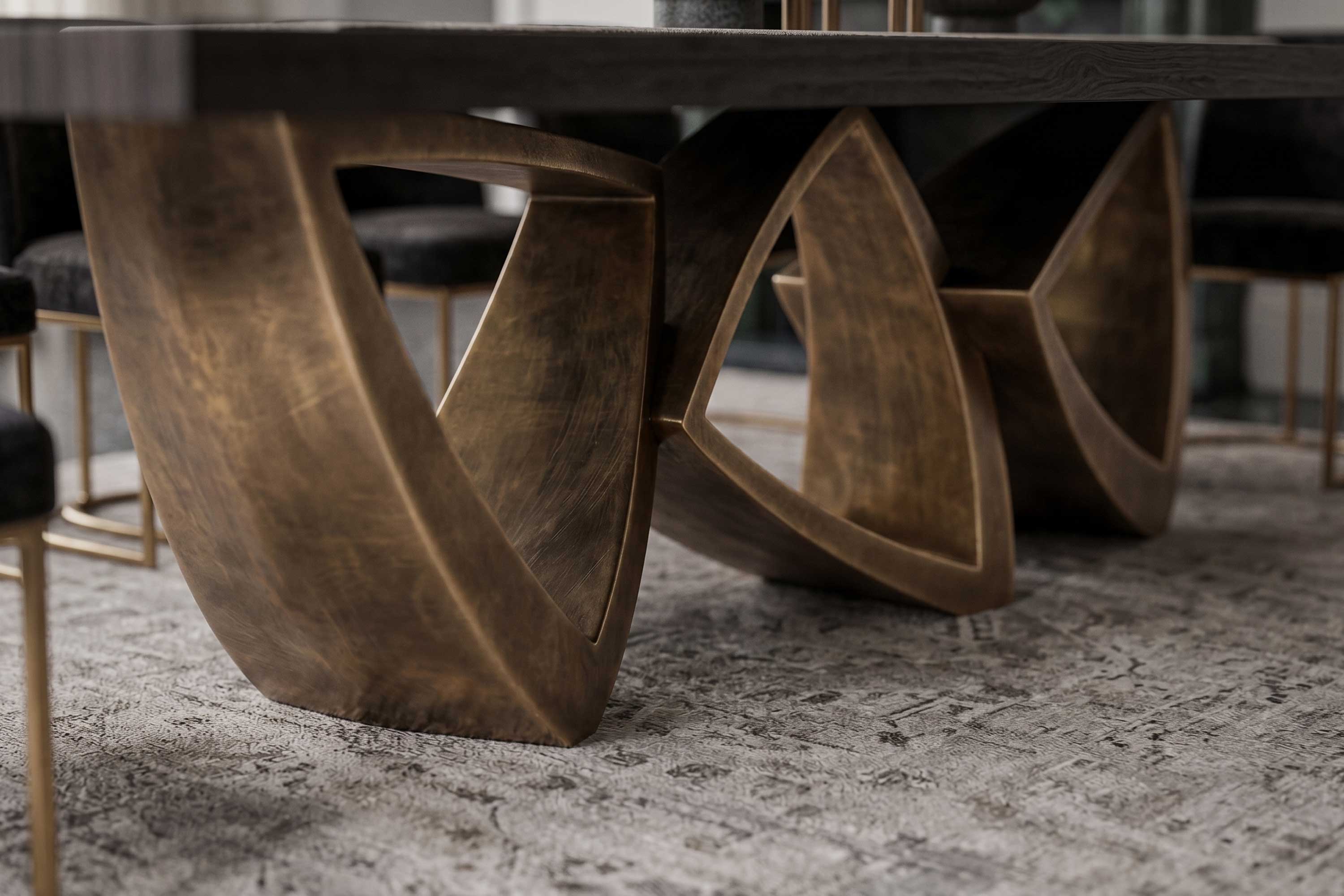 Arcos Dining Table in patina bronze, sculptural arc-base dining table staged in a dark editorial close-up detail view — Palena Studio