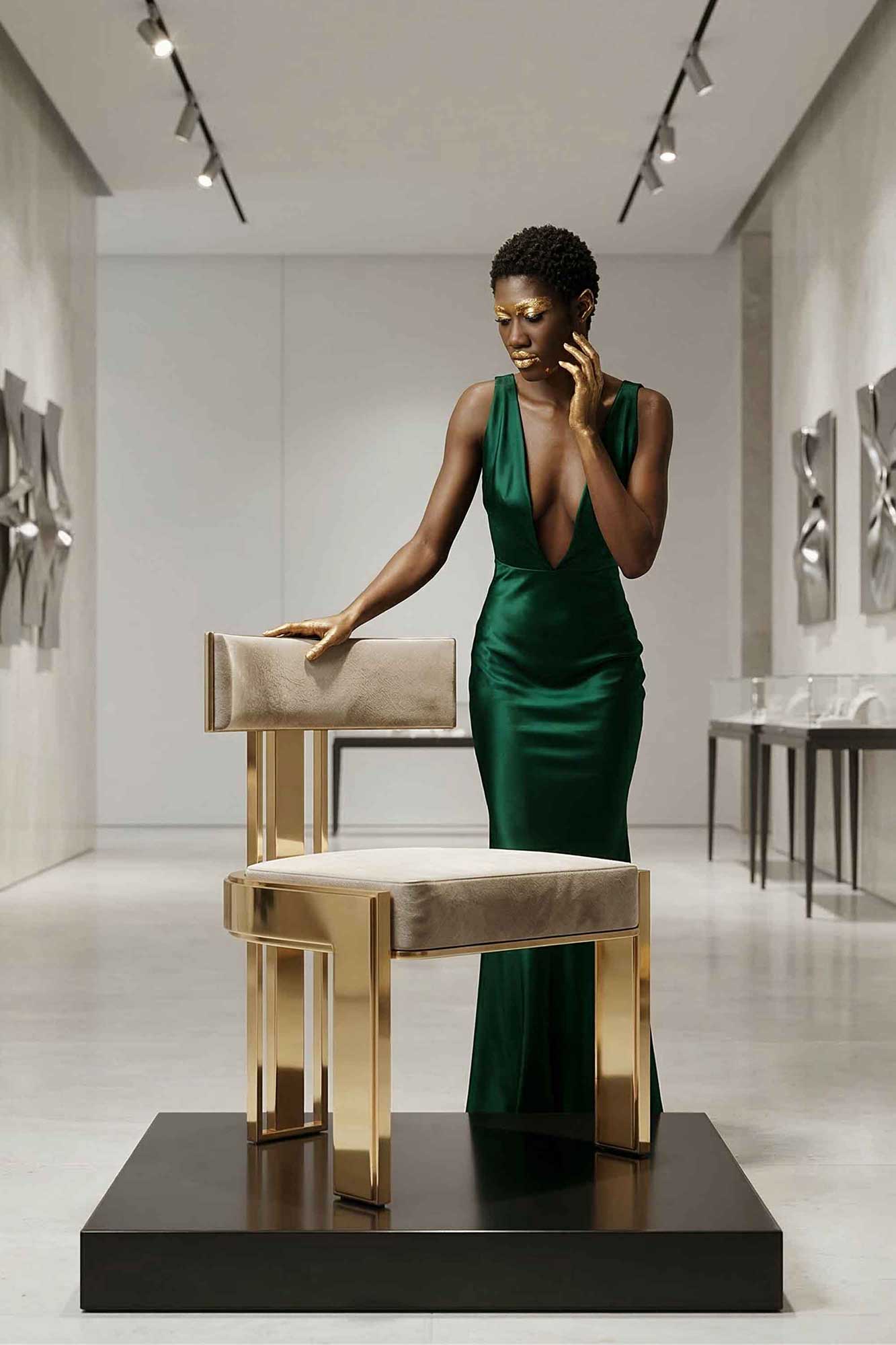 A woman in a green evening gown stands beside a modern chair with gold and beige accents, displayed on a black platform in a minimalist art gallery setting.