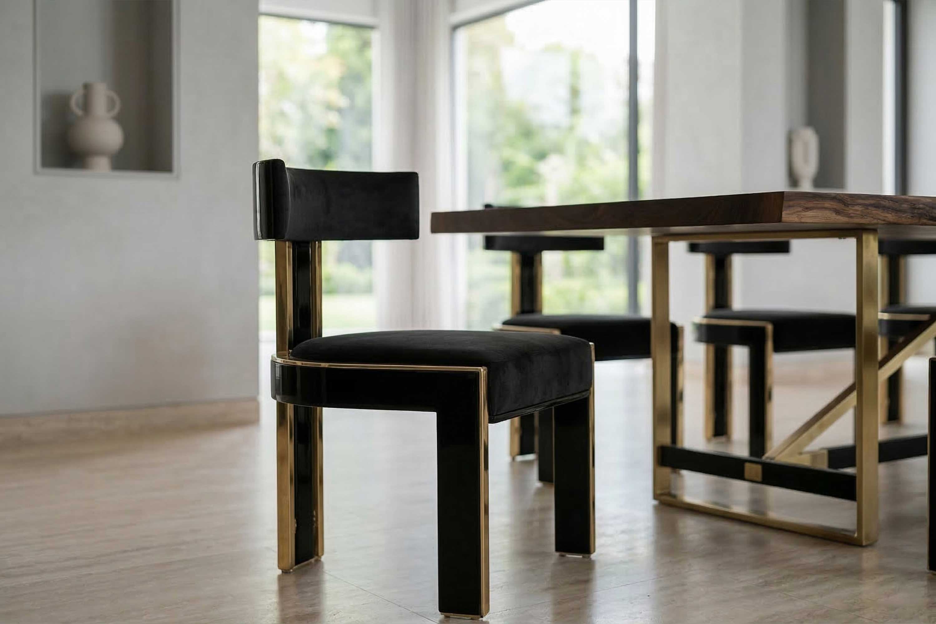 A modern dining room with a black and gold chair next to a wooden table. Large windows in the background let in natural light. The floor is light-colored, and there is minimal decor on the walls.