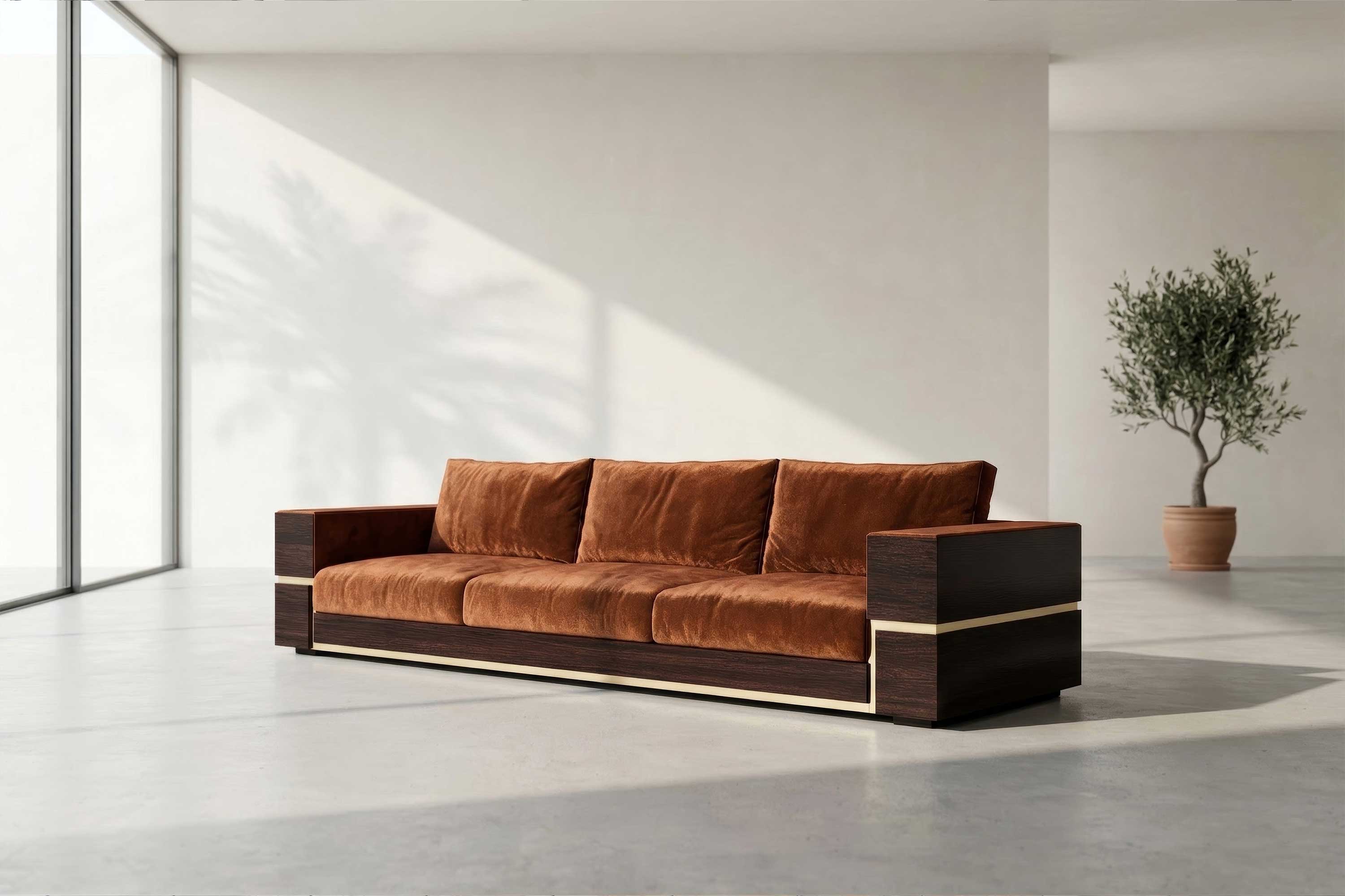 A modern brown sofa with a wooden frame and three seat cushions, crafted as bespoke furniture, sits in a bright, minimalist room. Sunlight casts a shadow of a palm tree on the wall, and a potted plant stands in the background.