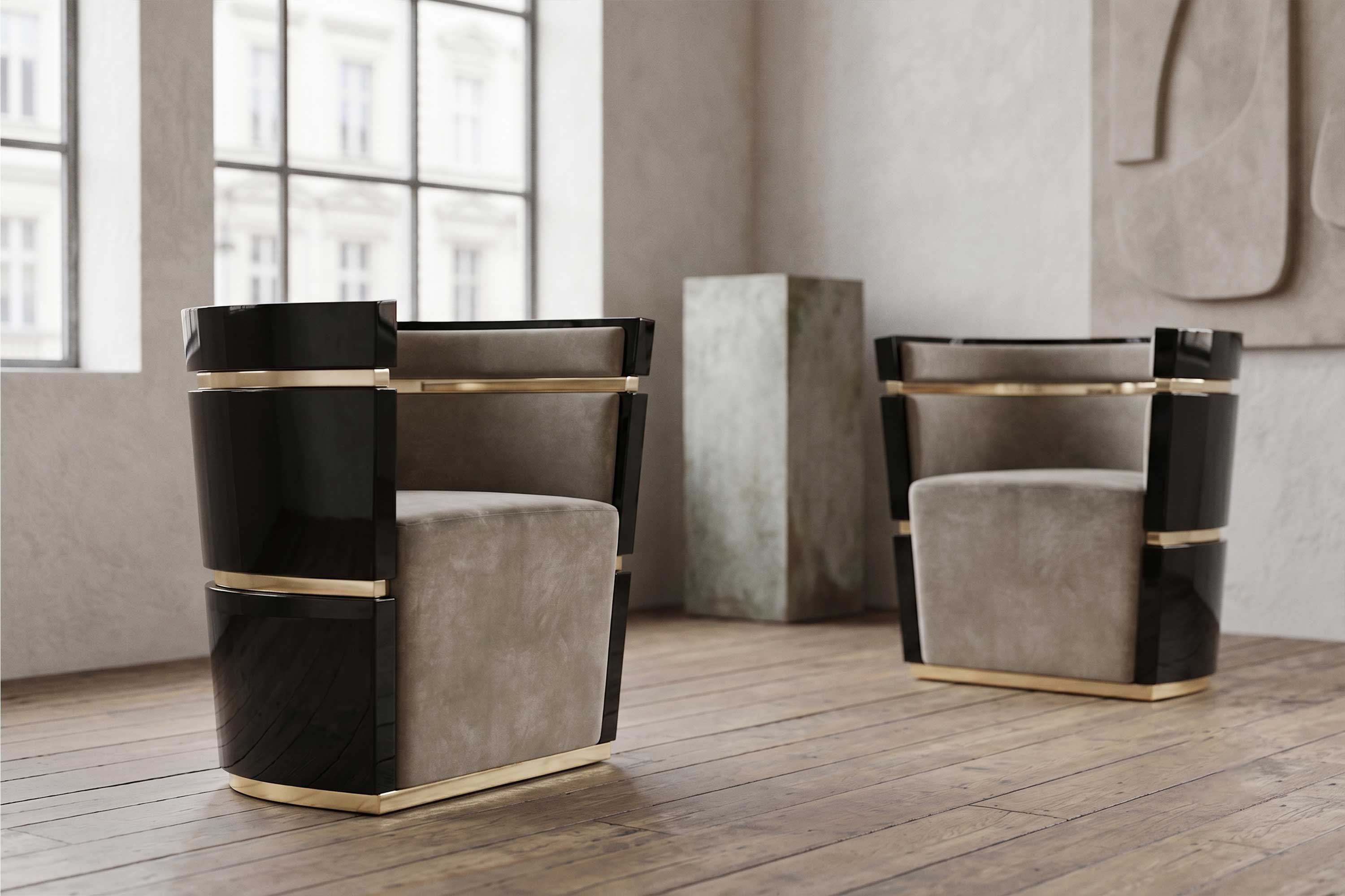 Two modern armchairs with black, beige, and gold accents are placed on a wooden floor in a bright room with large windows, neutral walls, and a rectangular pedestal in the background.
