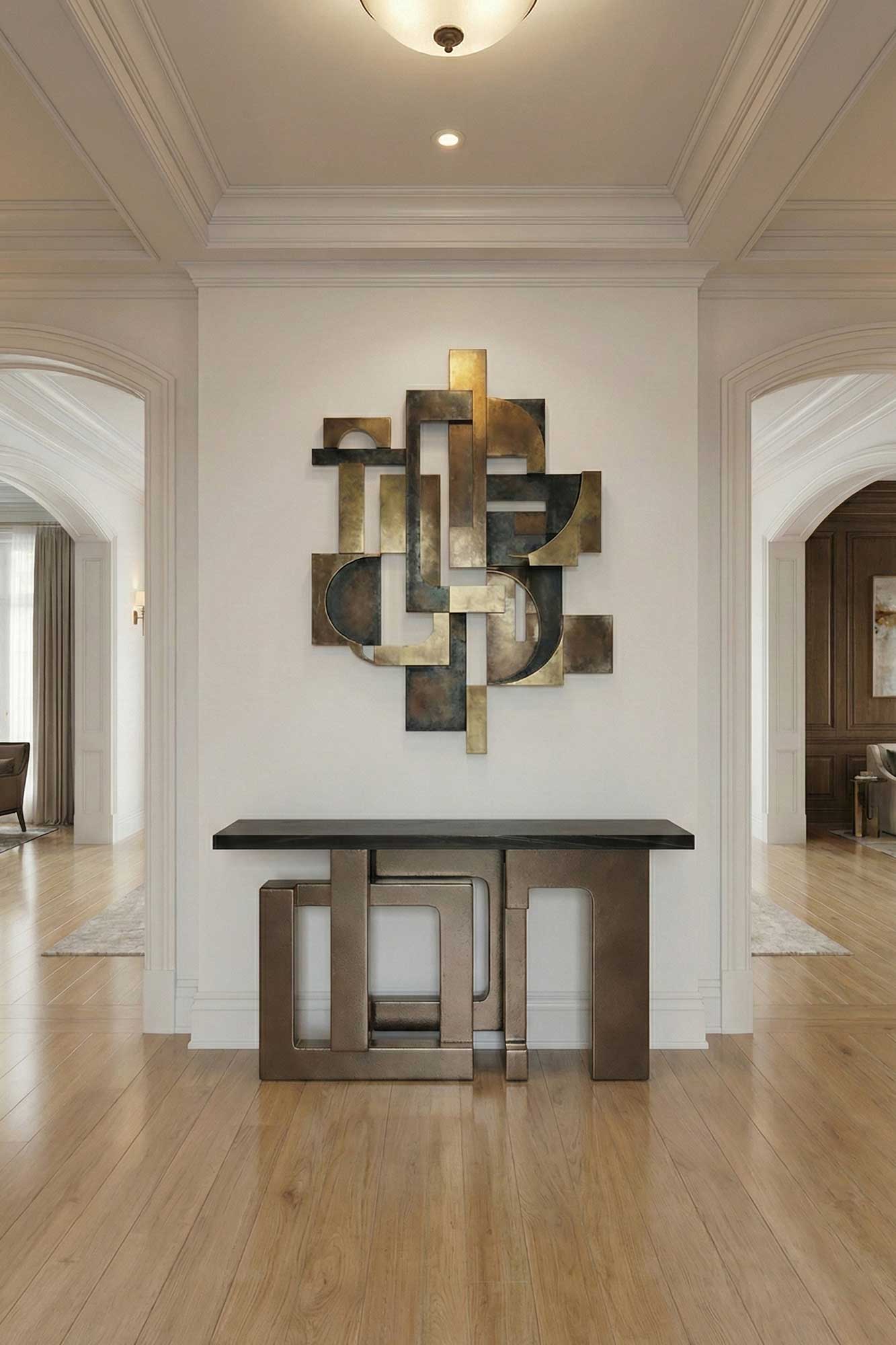 A modern entryway with light wood floors, a geometric bronze and black console table, and a matching abstract metal wall sculpture on a white wall under a ceiling light. Arched doorways lead to adjoining rooms.
