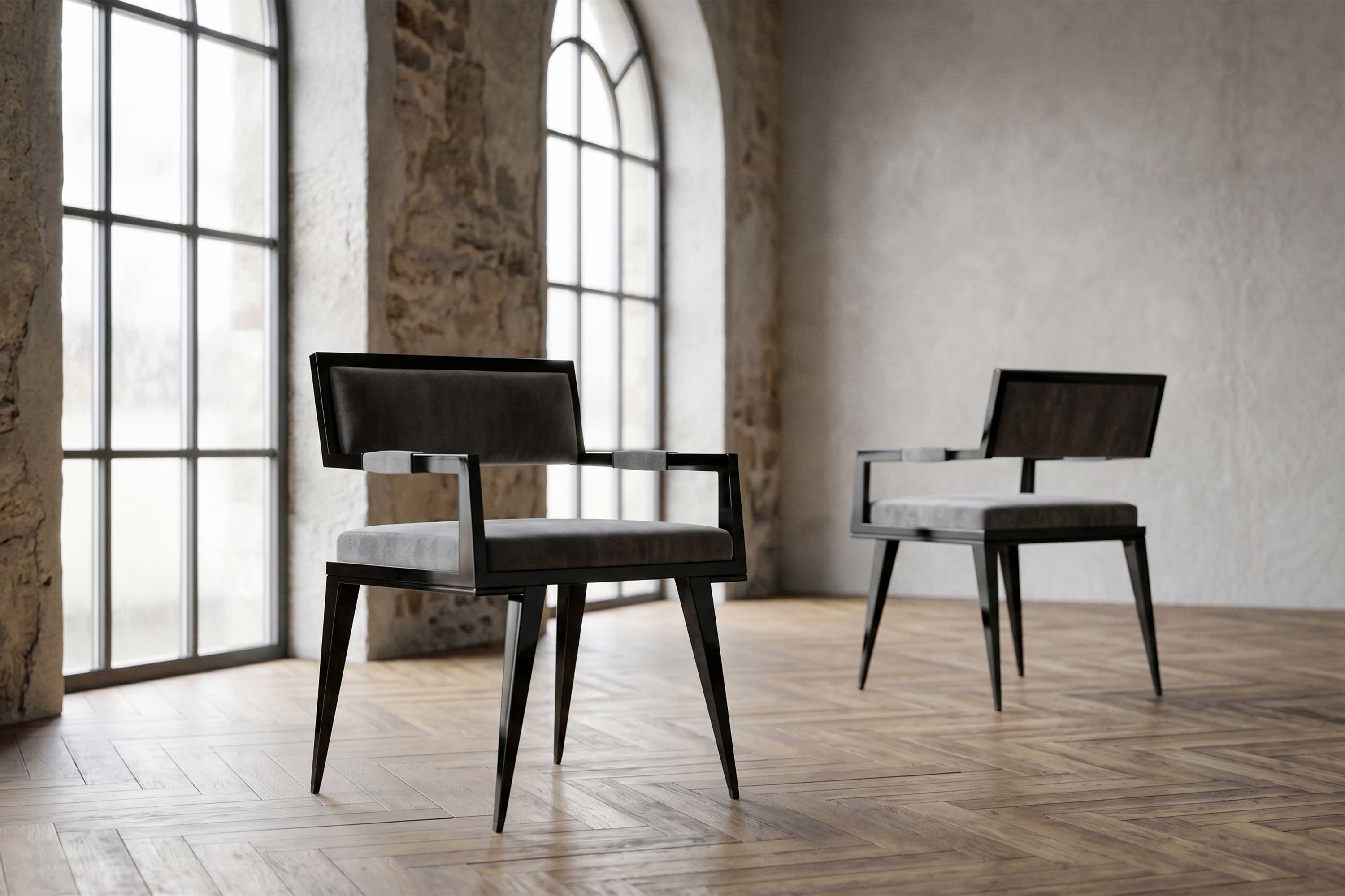 Two modern black chairs with grey cushions are placed on a wooden herringbone floor in a room with large arched windows and textured stone walls. Natural light fills the space.