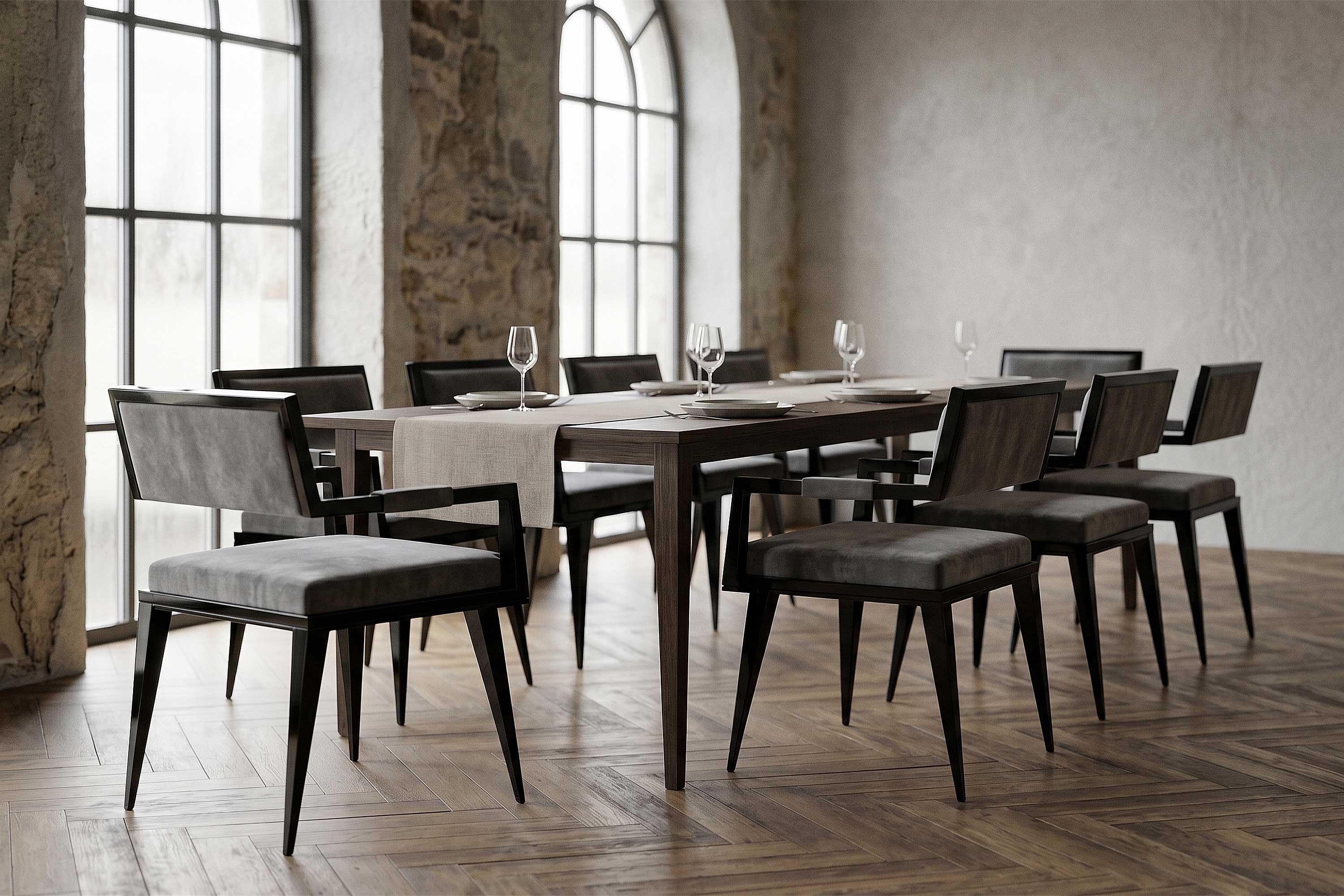 A rectangular dining table set with eight chairs, empty wine glasses, and plates is arranged in a spacious room with large arched windows, stone walls, and herringbone wood flooring.