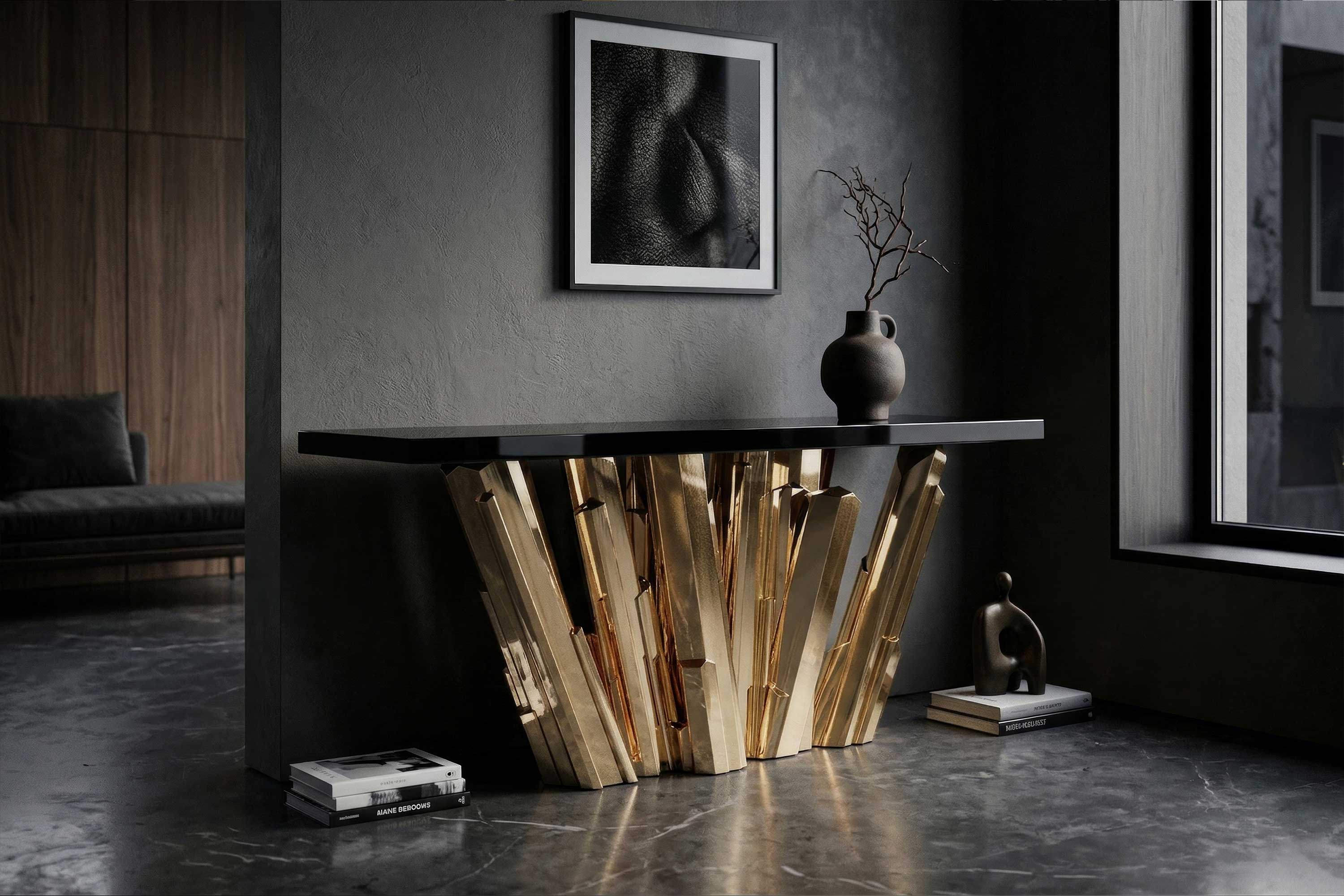 A modern room with a black-gold console table, abstract art on the wall, a vase with twigs, books on the floor, and a small sculpture near a large window. The floor is polished concrete.