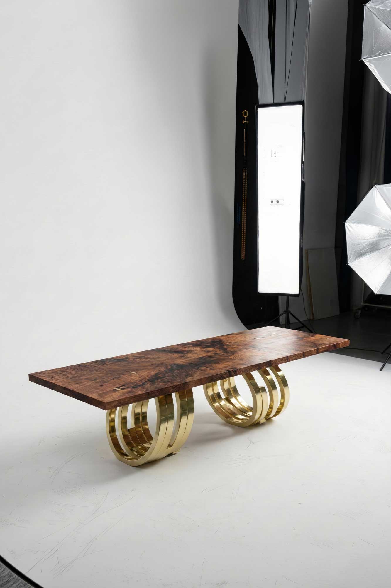 Oculus Dining Table in polished bronze, sculptural oval dining table staged in a dark editorial interior with floor-to-ceiling windows, Palena Studio