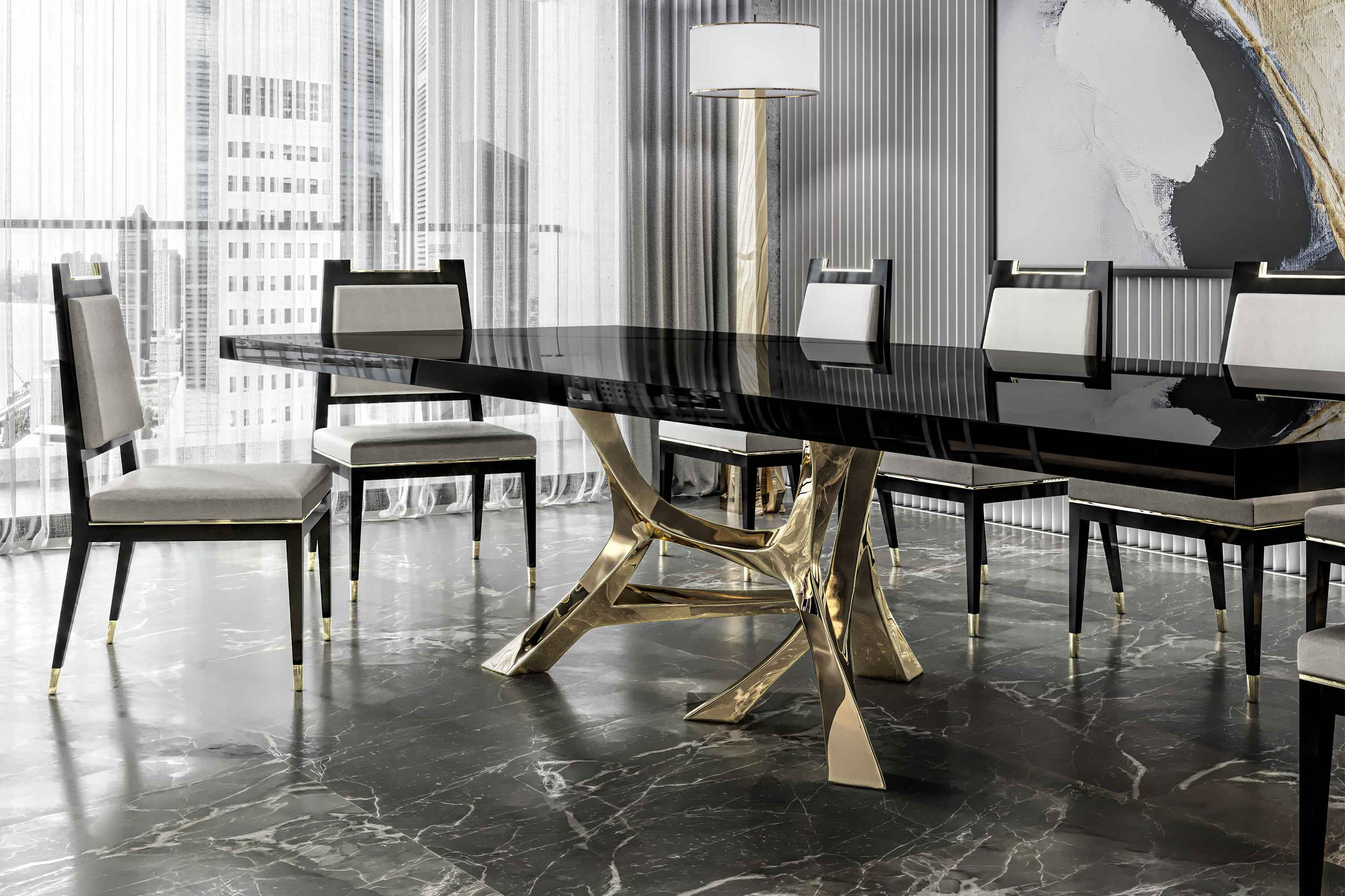 A modern dining room with a glossy black table supported by gold legs, surrounded by eight beige and black chairs. A tall floor lamp and abstract artwork are visible near large windows with city views.