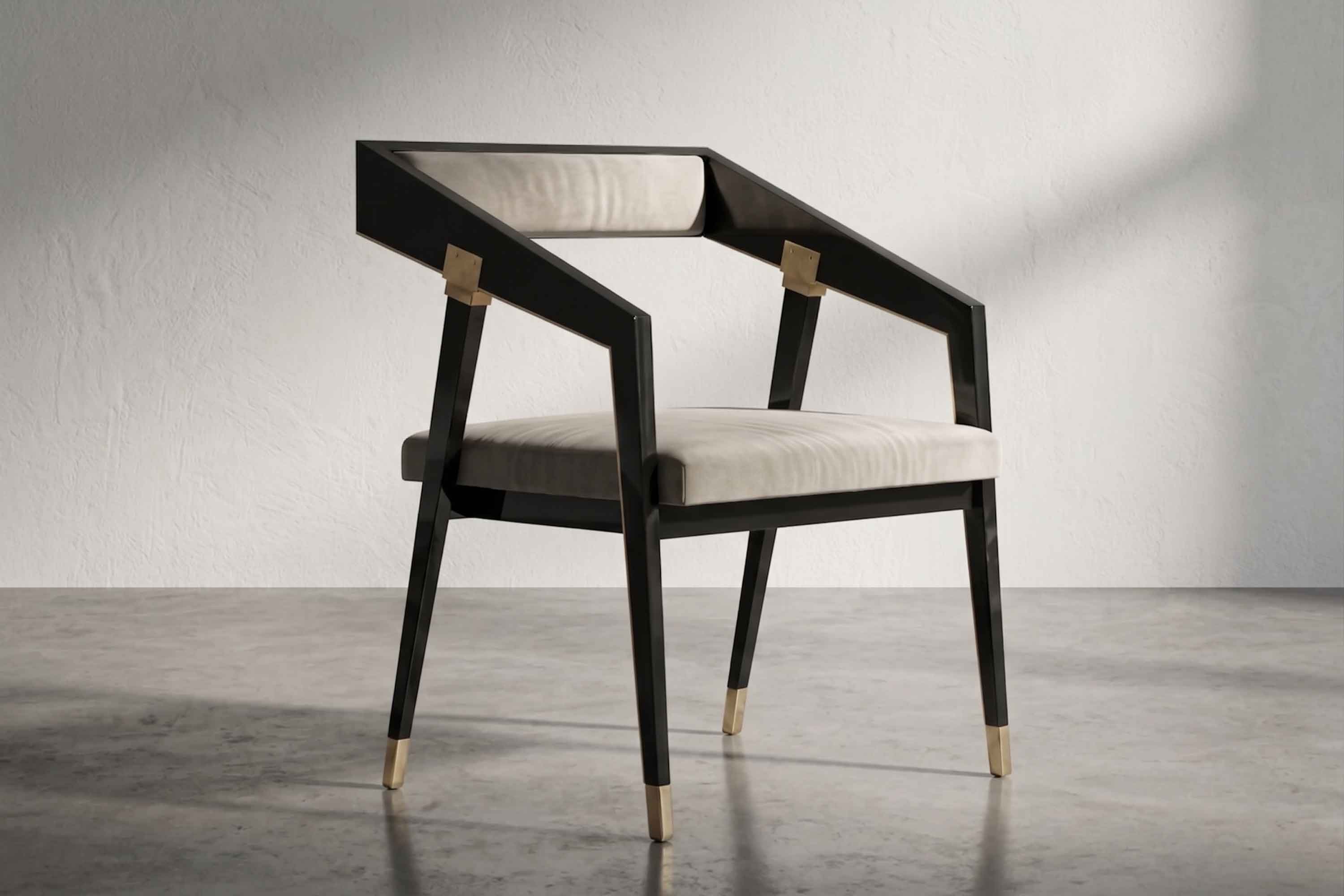 A modern armchair with a black angular wooden frame, beige cushioned seat and back, and gold accents on the arm joints and feet, placed on a grey polished floor against a plain white wall.