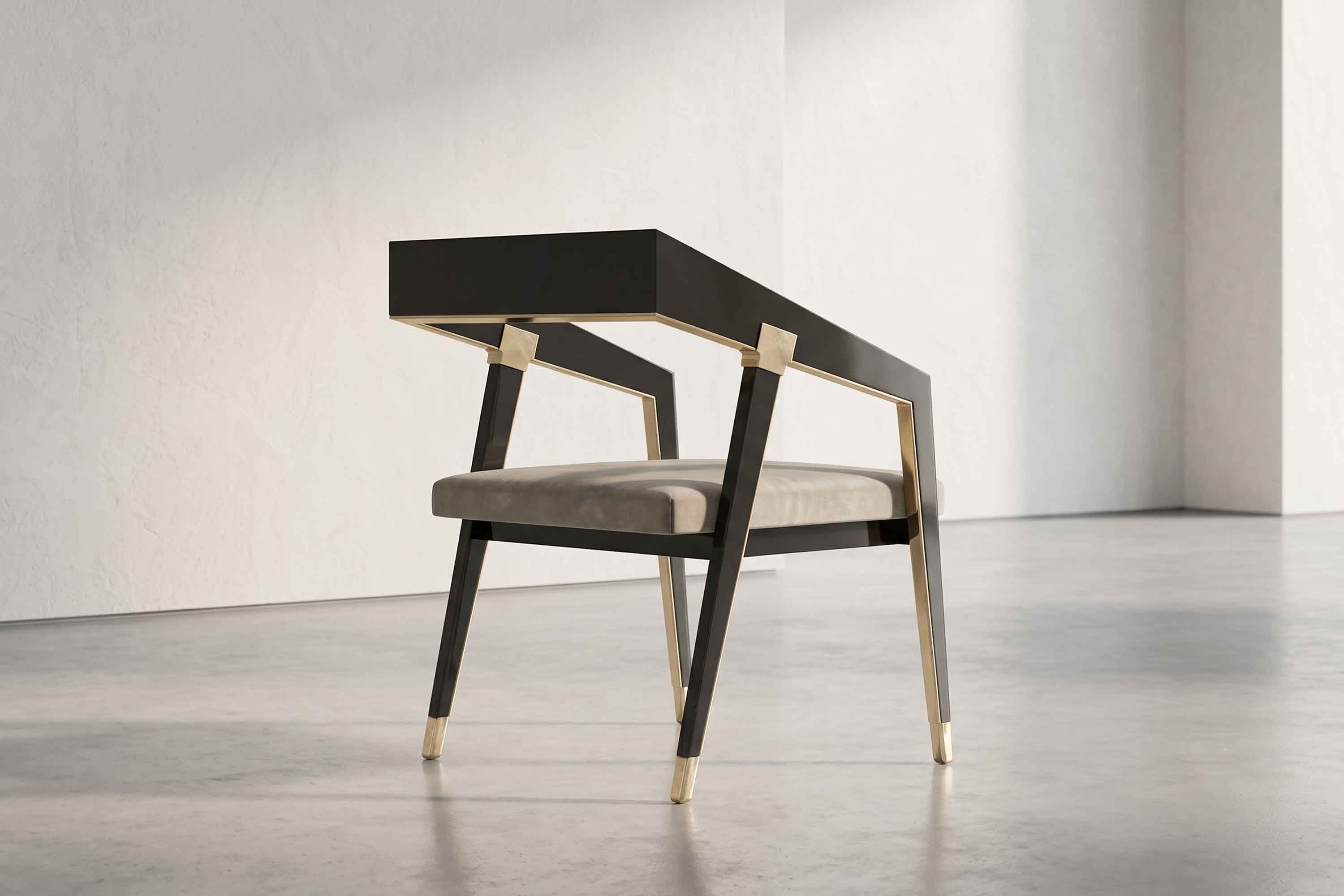 A modern chair with a black angular frame, gold accents, and a light gray cushioned seat sits on a smooth, light gray concrete floor against a plain white wall in a minimalistic setting.