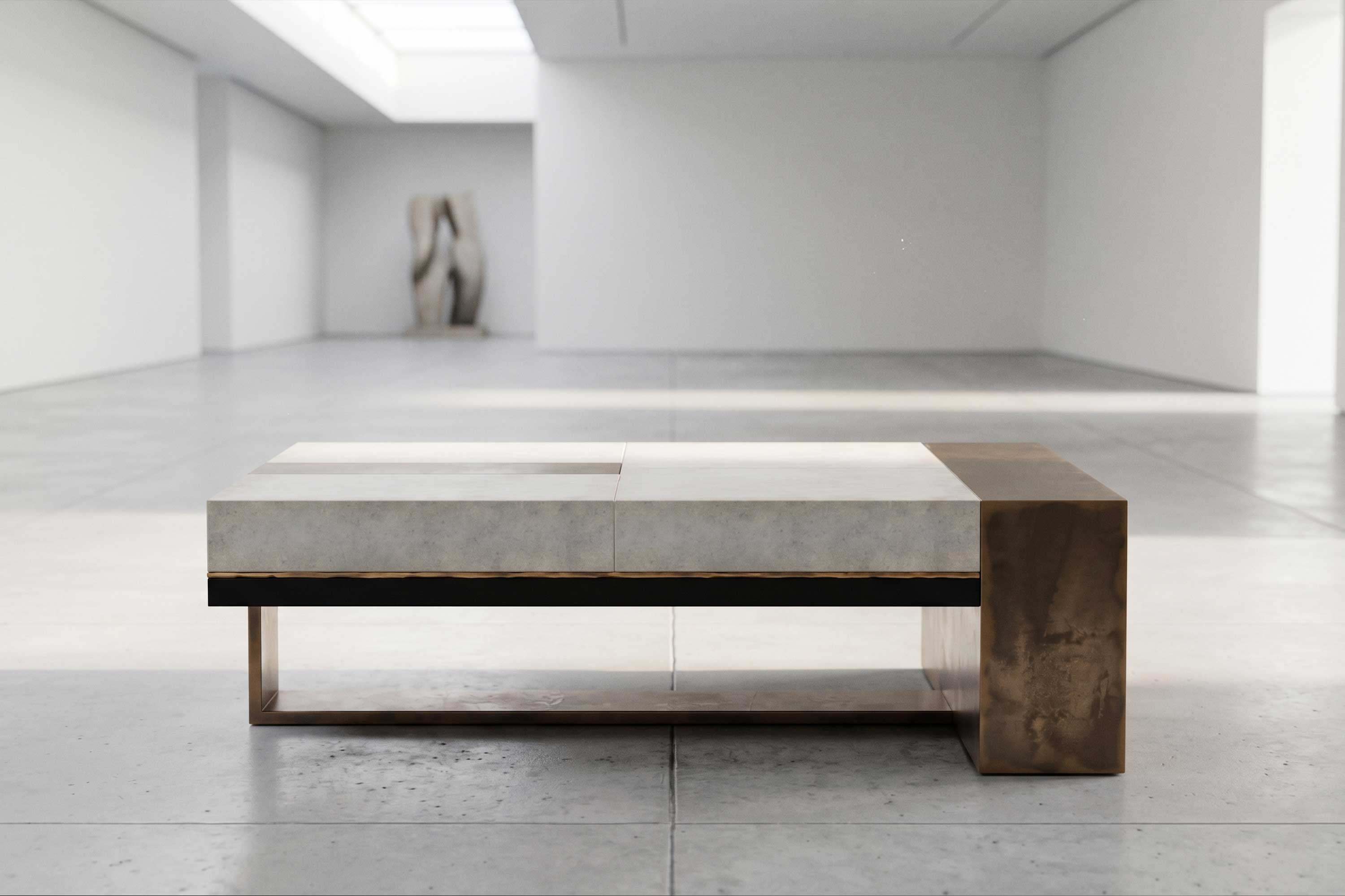 A modern coffee table with a minimalist design sits on a tiled floor in a spacious, empty gallery. The table has a mix of metal and stone textures; an abstract sculpture is visible in the background.
