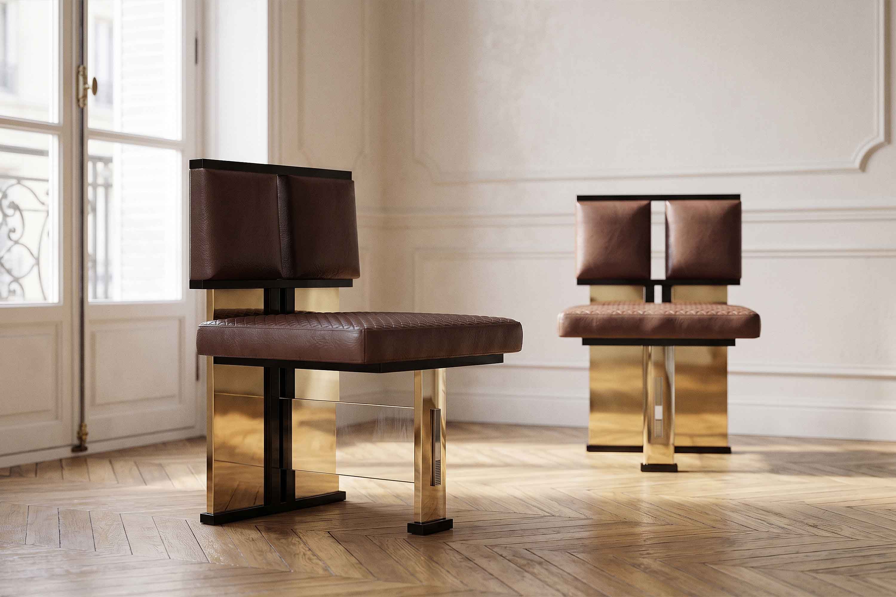Two modern chairs with brown leather seats and backs, and gold metallic bases, are placed in a minimally decorated room with wooden herringbone floors and white walls. Sunlight enters through tall windows on the left.
