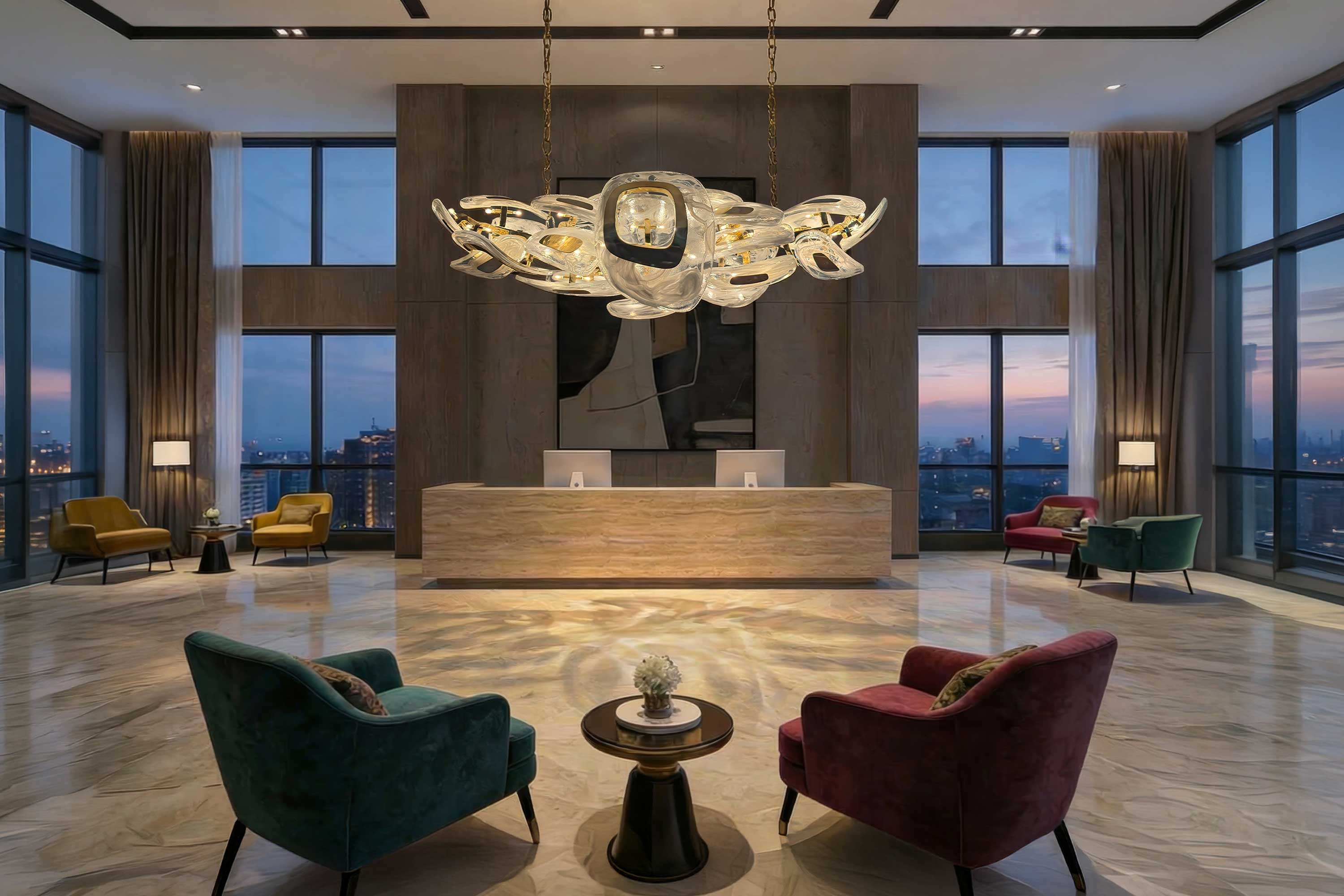 A modern hotel lobby with marble floors, two velvet chairs and a small table in the foreground, two reception desks in the center, large windows, tall curtains, and a decorative chandelier overhead.