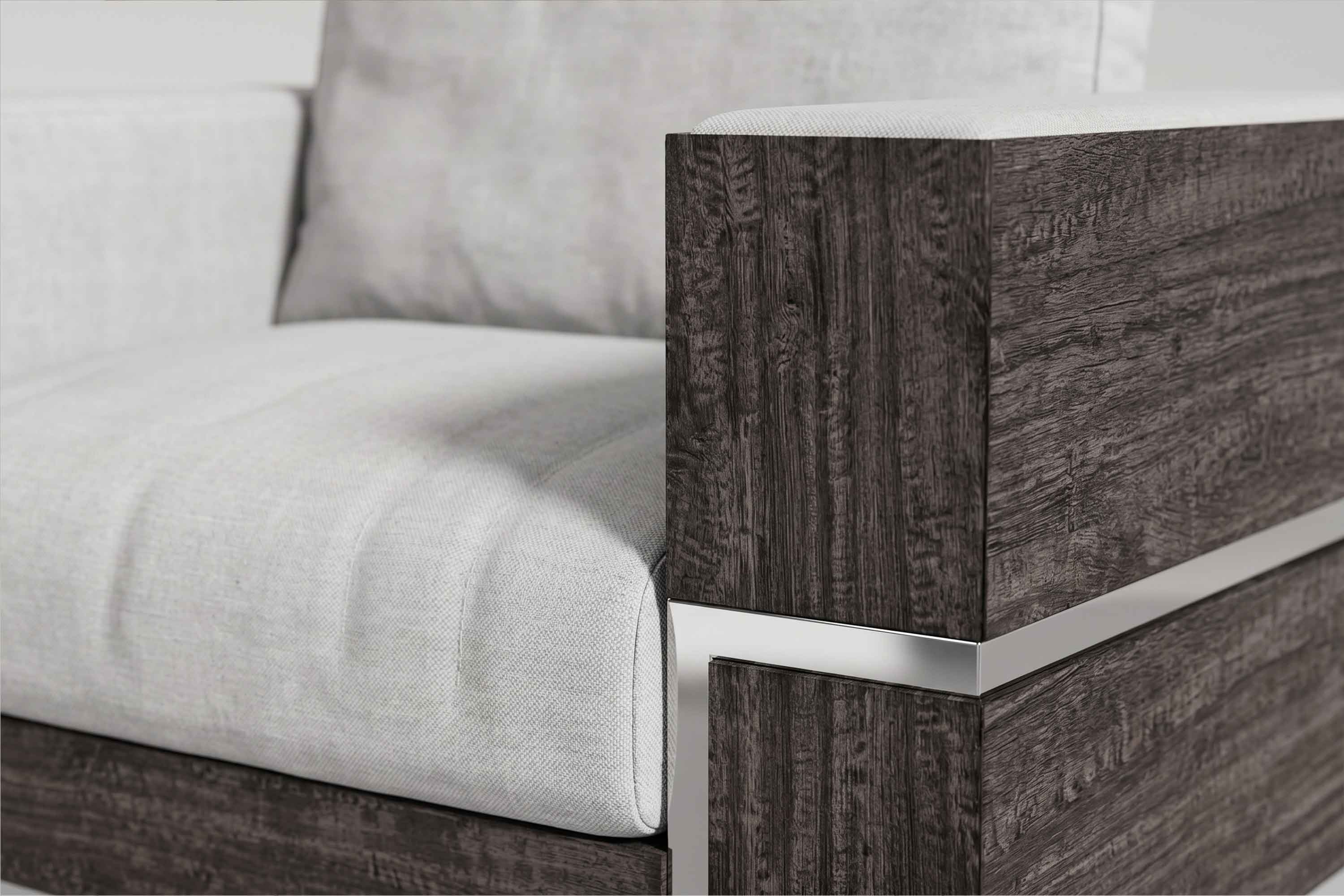 Close-up of a modern lounge chair featuring light gray fabric cushions and wide, dark wood armrests with a visible wood grain texture. This piece of bespoke furniture has a sleek, minimalist design with clean polished SS.