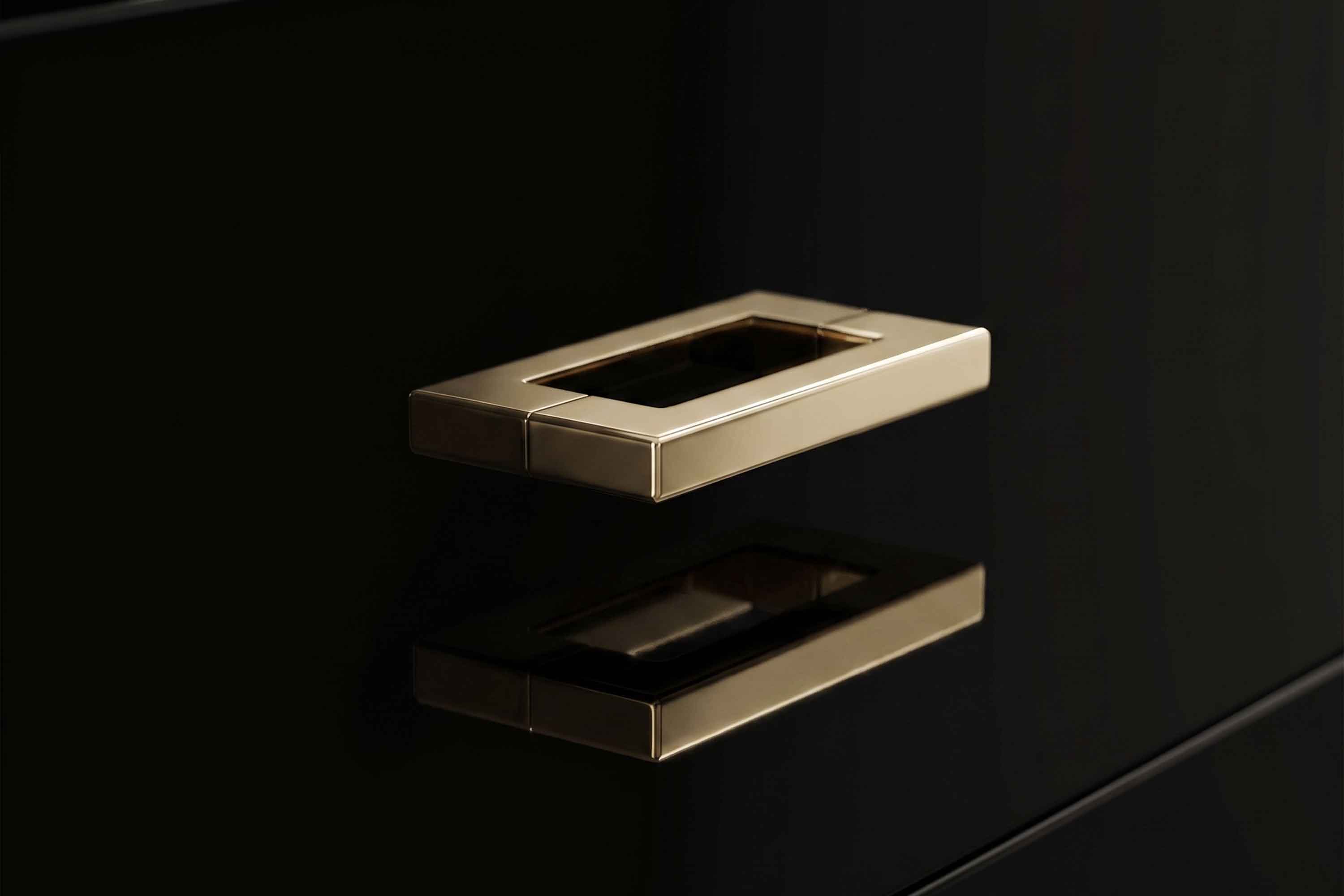 Close detail of the slim polished bronze pull handles set into the black lacquer drawer fronts of the Piano Console.