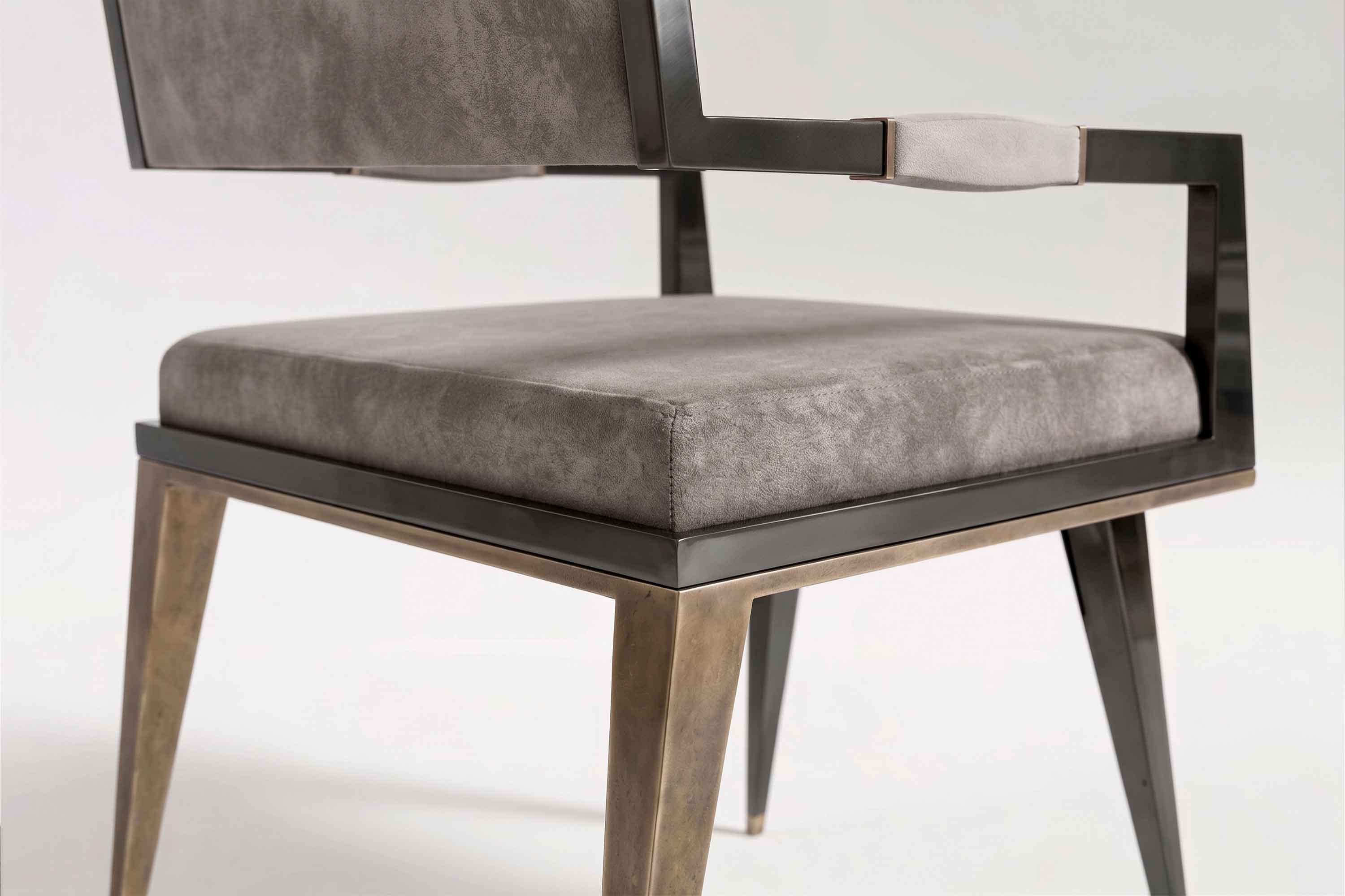 Close view of the Le Loup chair's seat, with the patina bronze leg tapering below the lacquered frame.