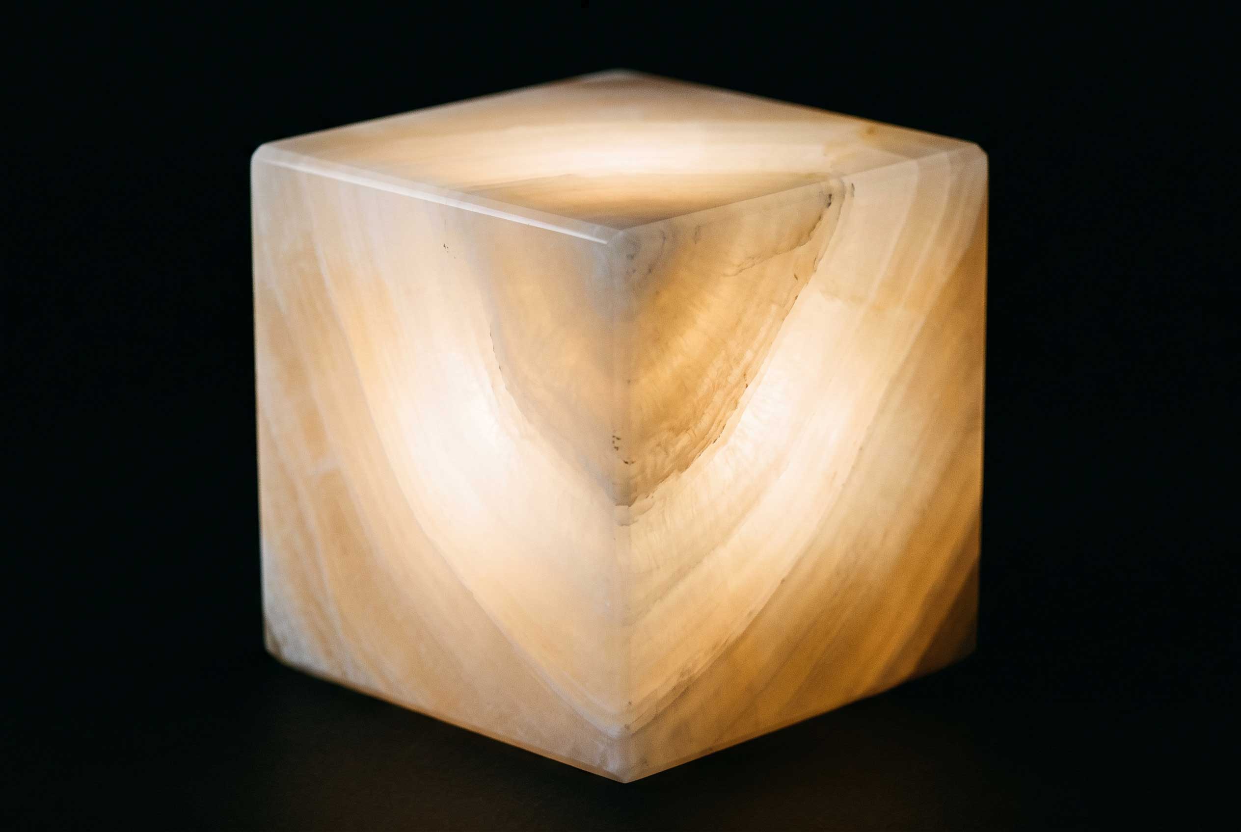 A cube of onyx glowing with light passing through its veining