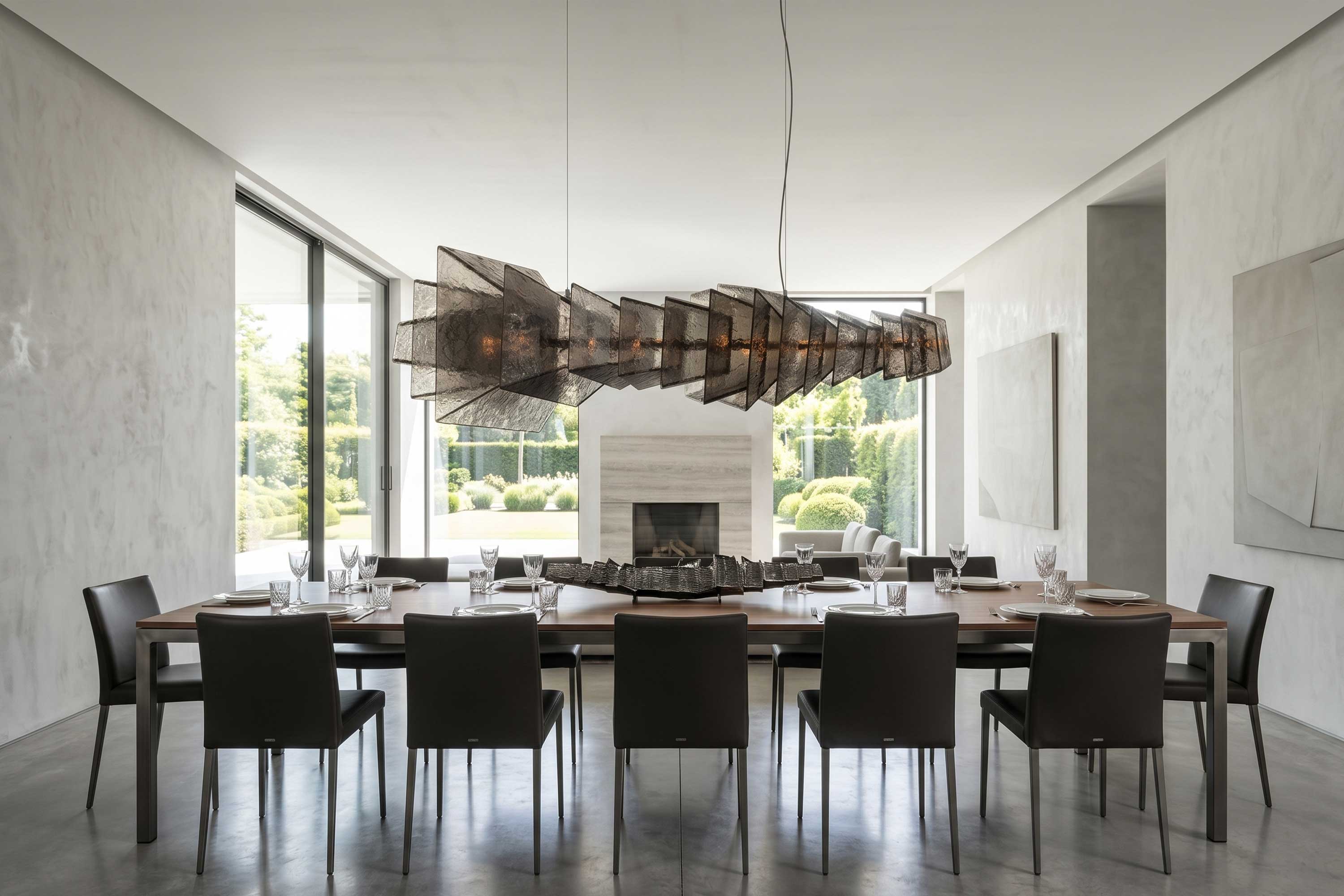 Gellus chandelier in frosted cast glass with a polished bronze core, above a long dark table in a contemporary interior with garden views — Palena Studio