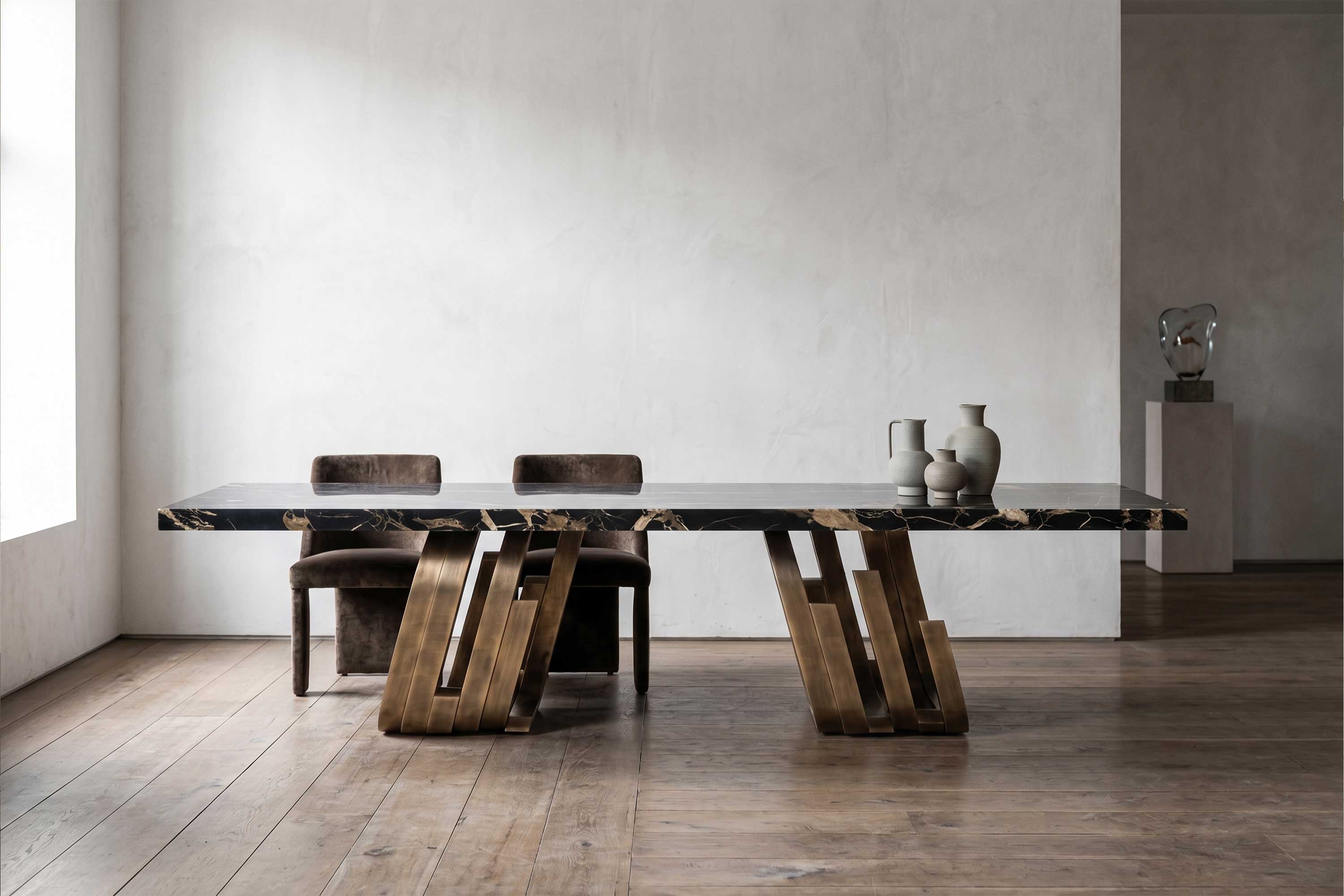 Oculus Dining Table in patina bronze with a Nero Portoro marble top, dual pedestal base staged in a pale minimal interior with a sculpture on a plinth — Palena Studio